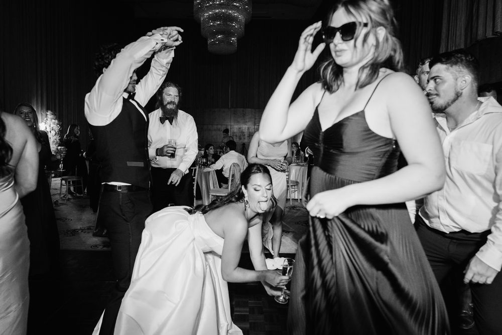 Black and white photo of wedding reception dance party with guests celebrating.