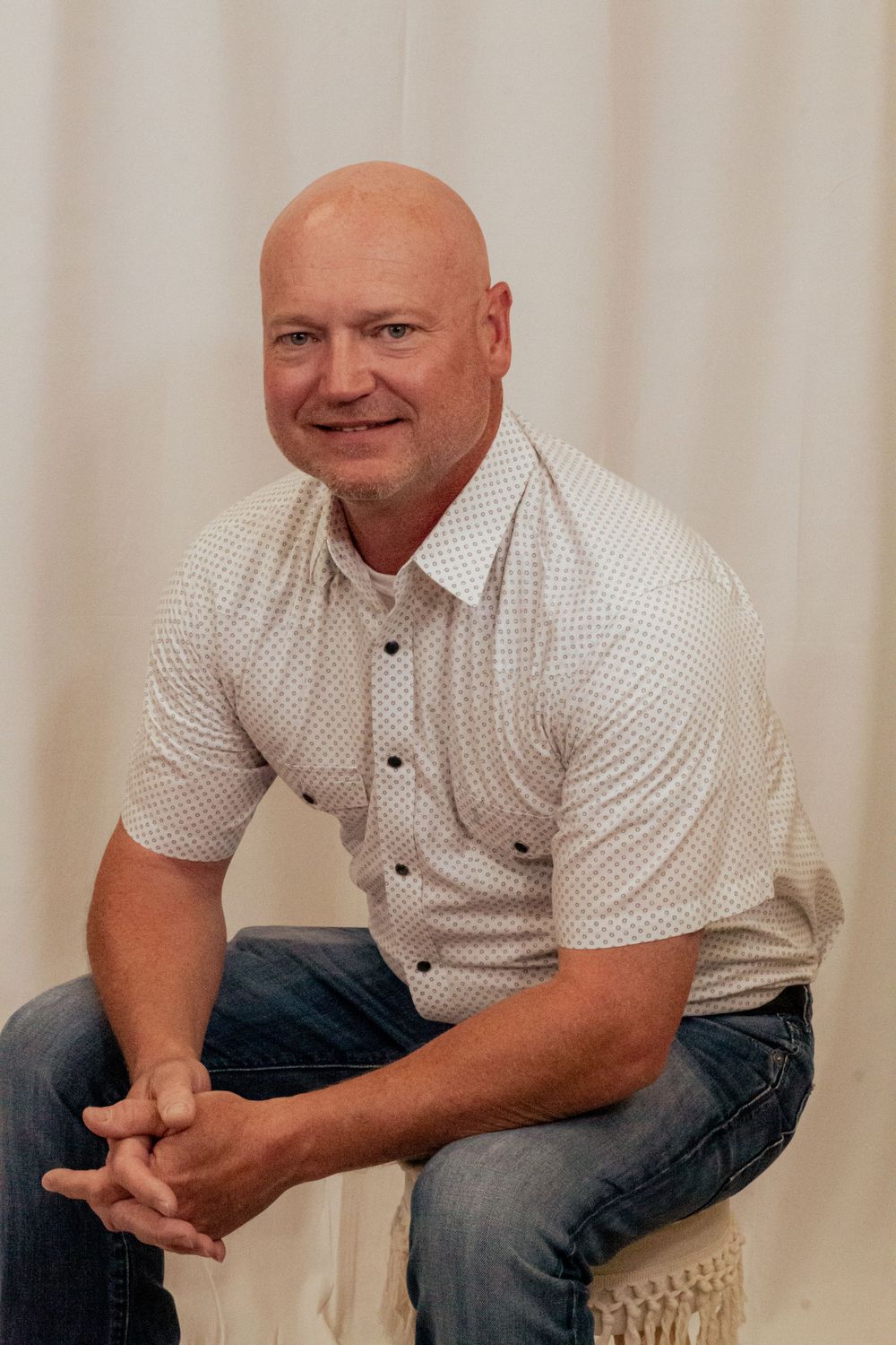 Four sequential photos show someone sitting and smiling in casual attire against a light colored wall.