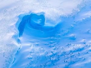 Abstract patterns of blue ice form a natural cave ceiling with intricate crystalline textures.