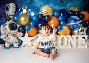 Space themed first birthday photoshoot with balloon decorations featuring astronauts, stars, and planets.