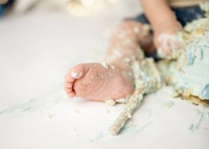 Close-up view of a young child's hands playing and making shapes in flour or dough on a kitchen counter.