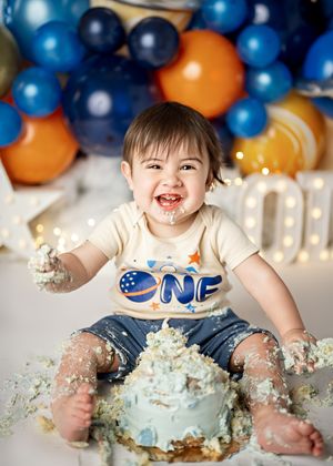 First birthday smash cake photo sequence showing excited baby in blue and white outfit playing with cake and frosting.
