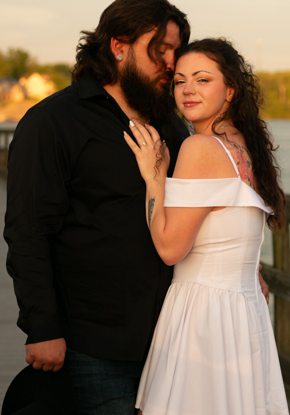 A romantic sunset portrait of a couple embracing, with the woman in a white dress and man in dark clothing.