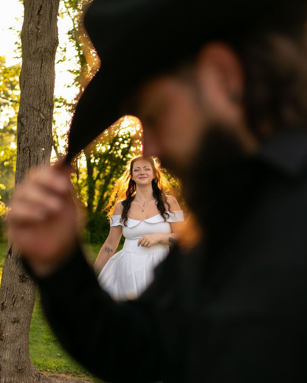 Creative wedding photo composition framing a bride in a white dress through an out-of-focus silhouette in the foreground.