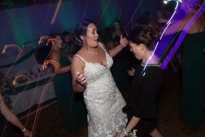 People dancing at a wedding reception with colorful lighting effects and blurred motion in the background.