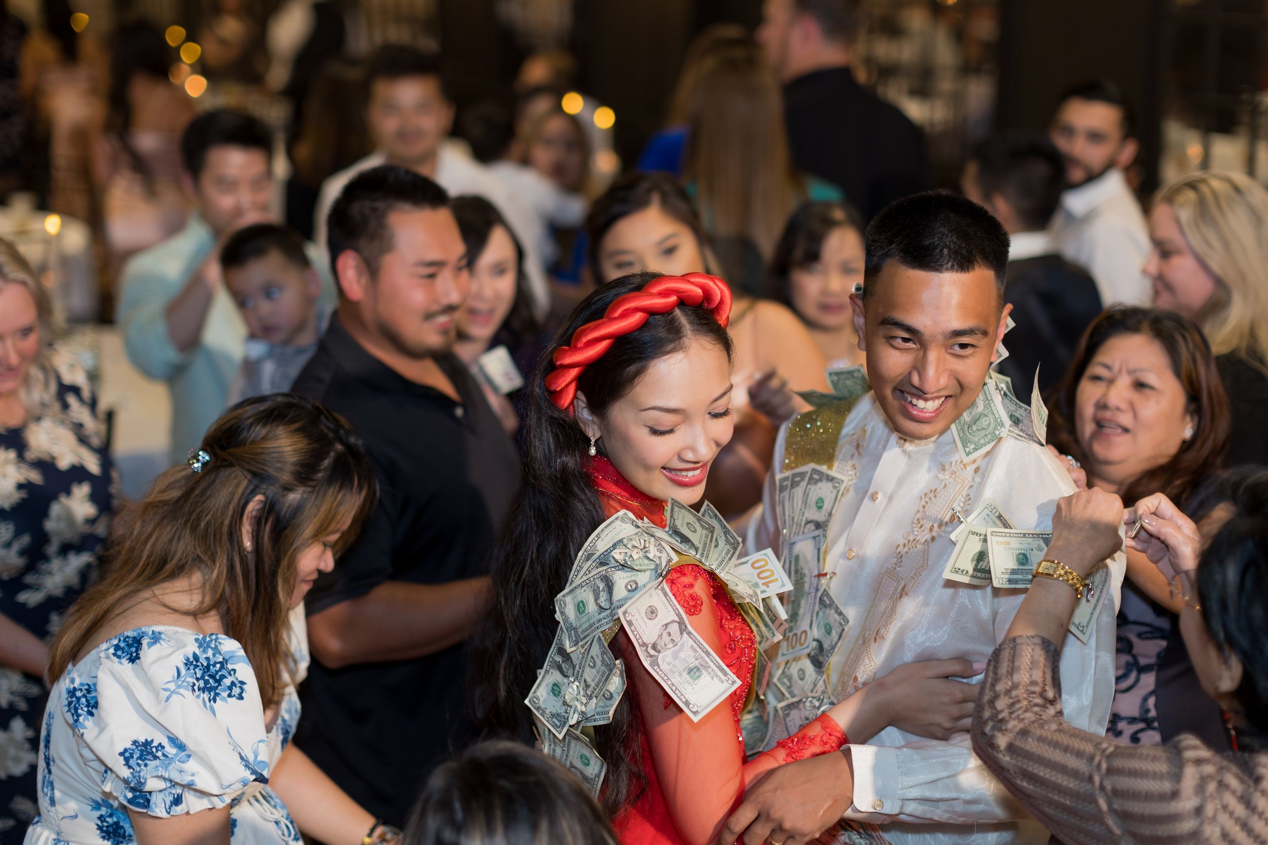 Wedding guests react with emotion and laughter during a lively reception celebration.