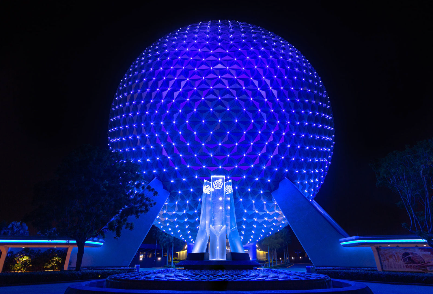 Spaceship Earth at EPCOT illuminated in blue lights during nighttime.