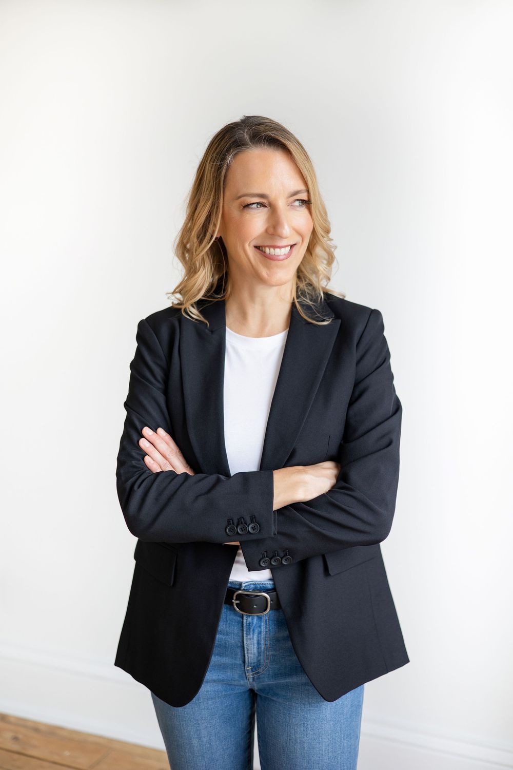 Professional accountant in a navy blazer with a white t-shirt and jeans with arms crossed for her headshot photography session in London.