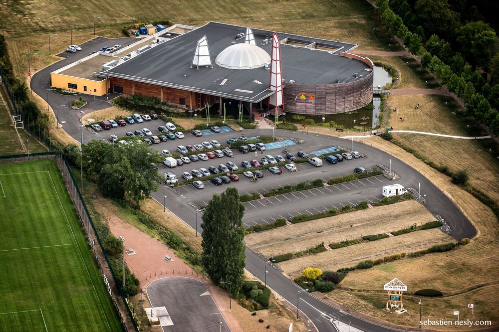 Vue aérienne des bâtiments du campus institutionnel et des parkings entourés d'aménagement paysager.