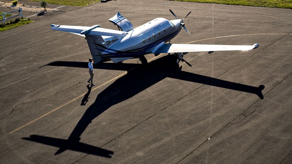 Petit avion privé stationné sur un tarmac de béton sous la lumière du soleil.