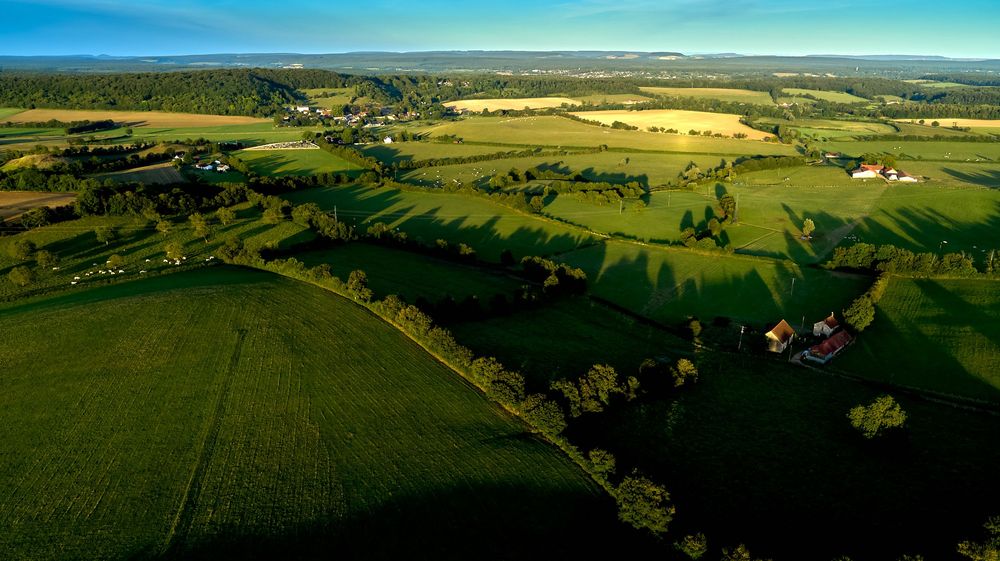 Sweeping panoramic view of rural farmland and rolling hills under blue skies.