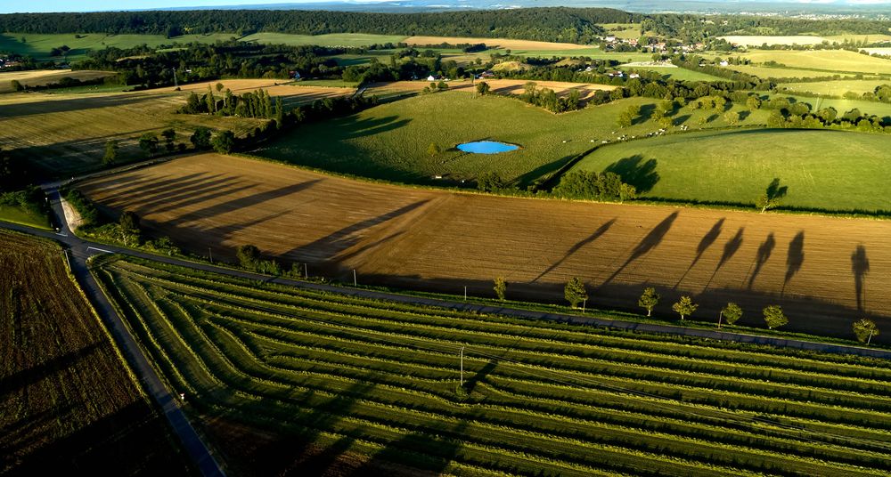 Paysage agricole gallonné avec des champs de culture, un petit étang qui s'étend à travers la campagne par une journée ensoleillée