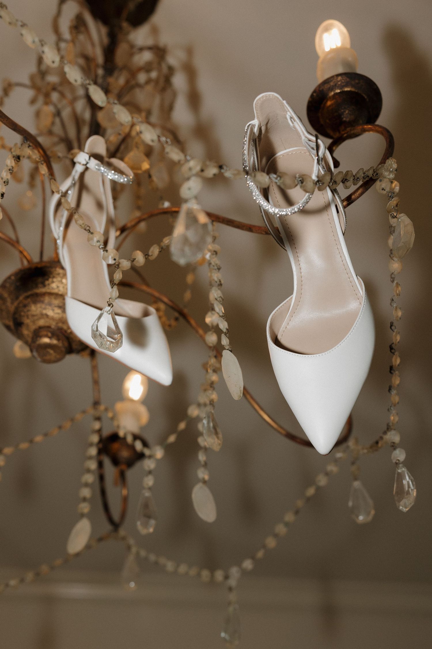 Editorial style details of brides shoes hanging from elegant chandelier at The Bower wedding Venue in Edmond, Oklahoma.