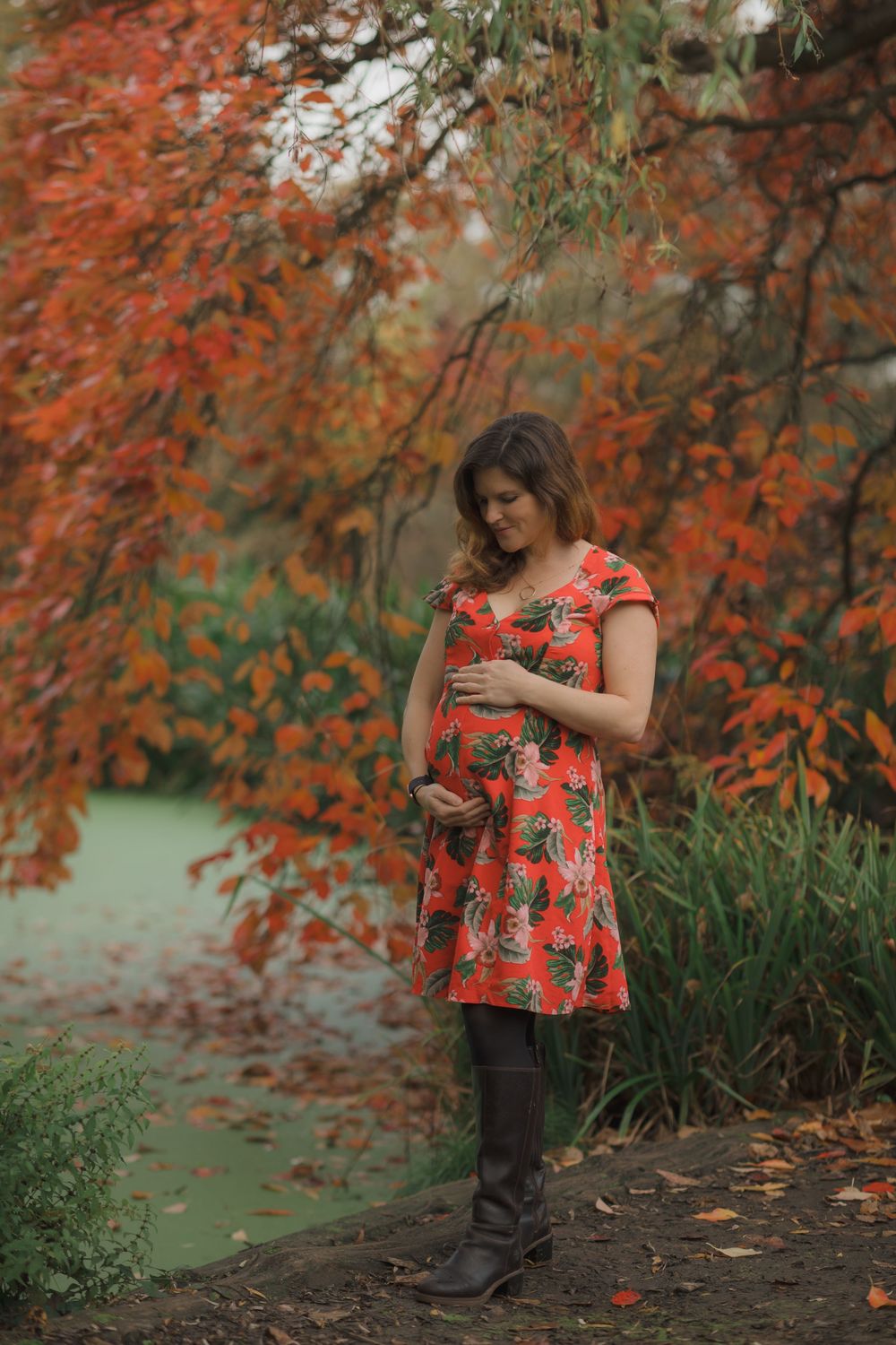 Red floral dress captured in autumnal garden setting with orange leaves and greenery.