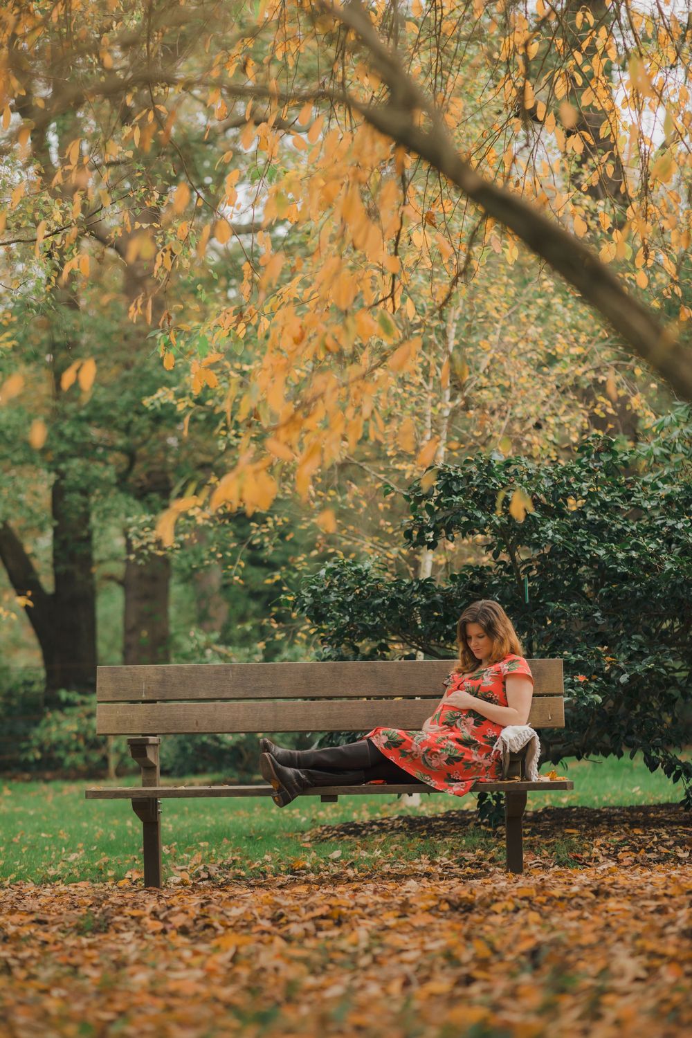 Red floral dress shown against autumn backdrop with park bench and fallen leaves.
