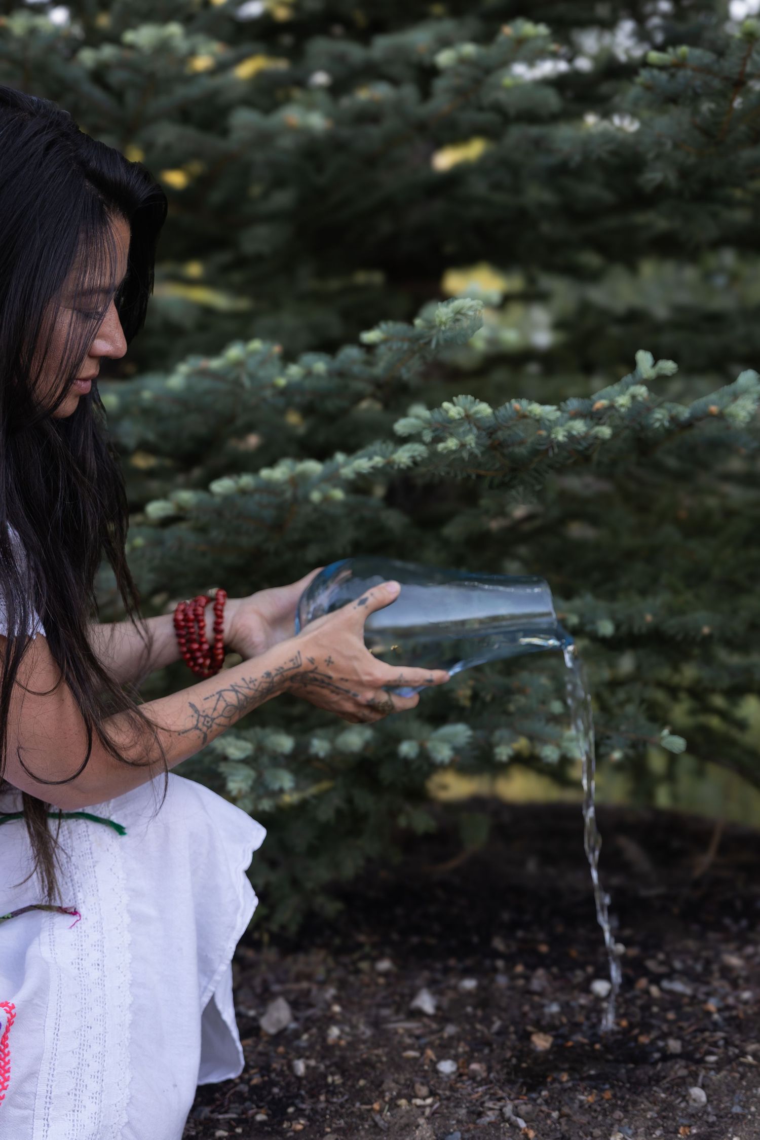 Woman pours water for a land offering during a ceremonial event photo session by Terra Firma Photography.