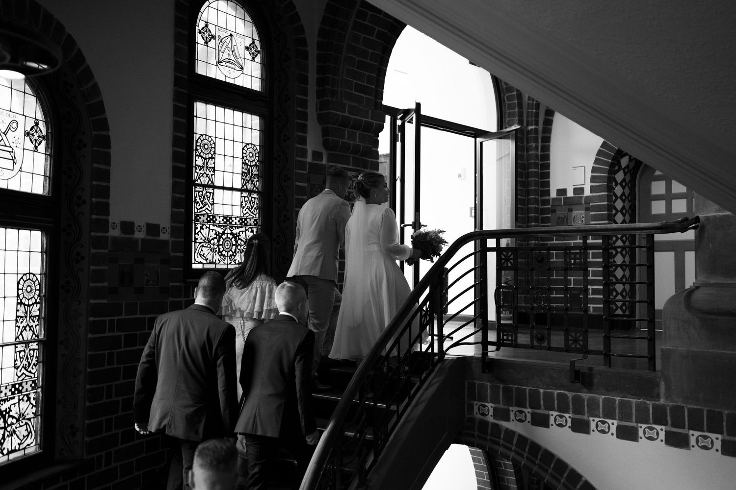 Hochzeitsfotograf Schloss Köpenick Berlin – Brautpaar läuft mit Gästen Treppe hoch Schwarz-Weiß