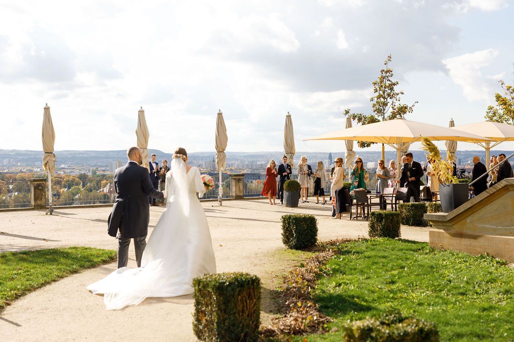 Wedding ceremony setup at an outdoor venue with stunning hilltop views, beige umbrellas and manicured lawn decorations.