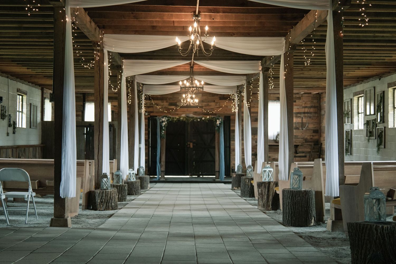 Interior of an industrial warehouse space with exposed wooden beams, hanging lights and long empty hallways.