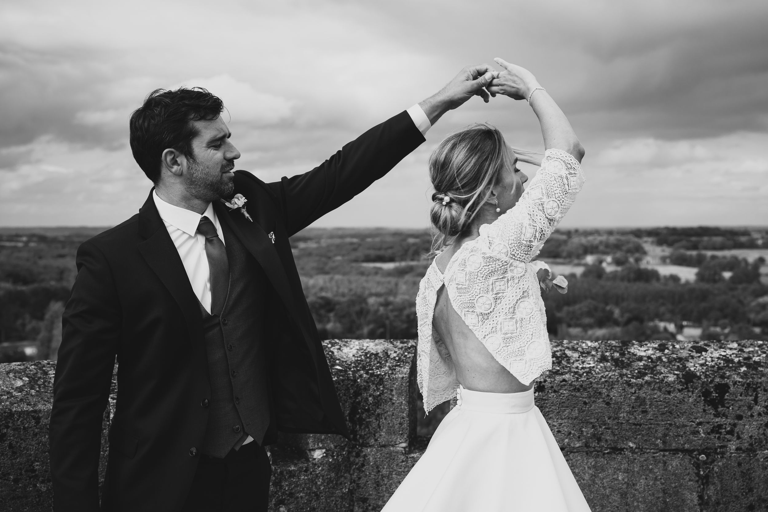 A couple celebrates their wedding day in a scenic outdoor setting, their silhouettes dramatic against a moody sky.