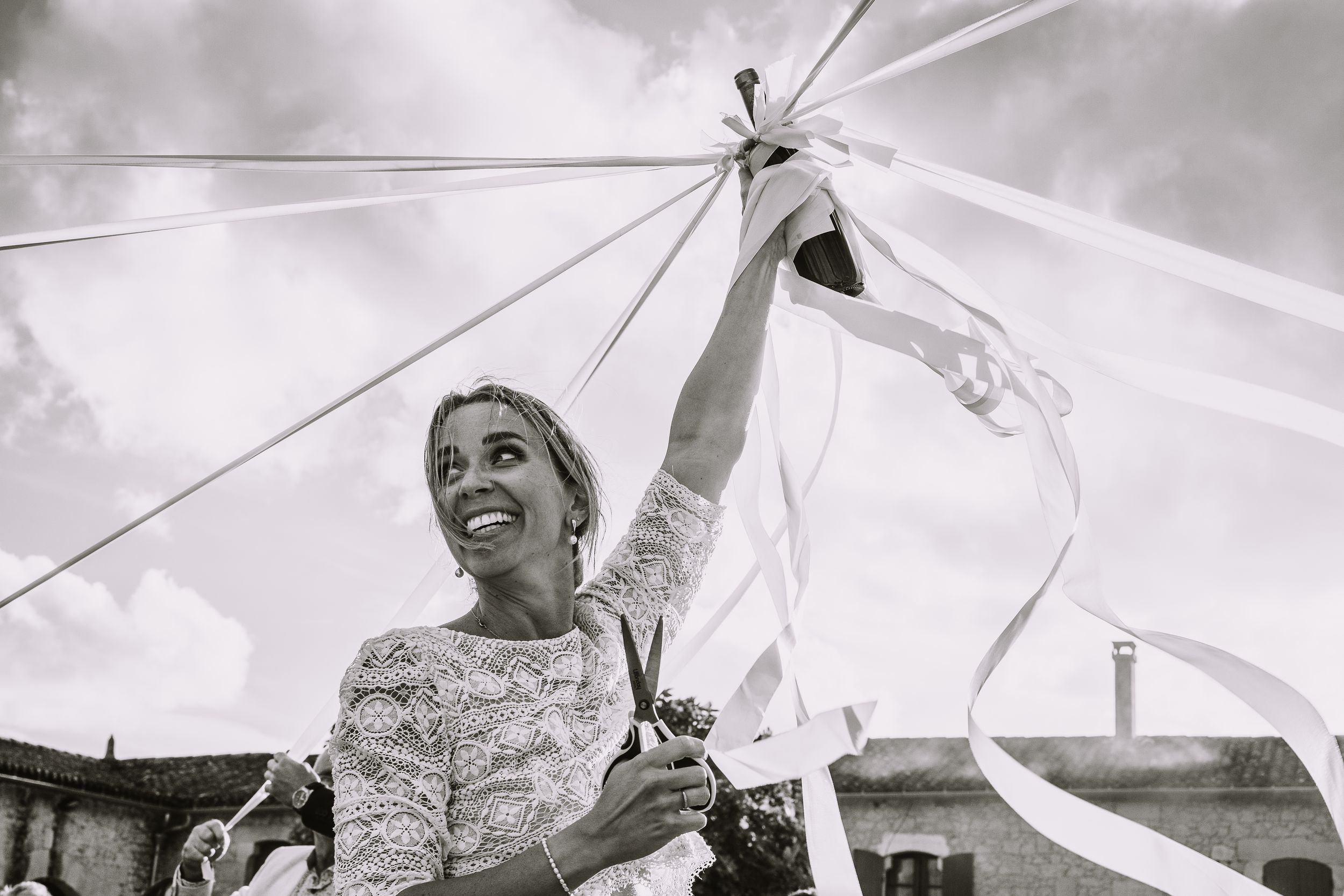 Black and white photo series showing joyful wedding moments under white umbrellas on a cloudy day.