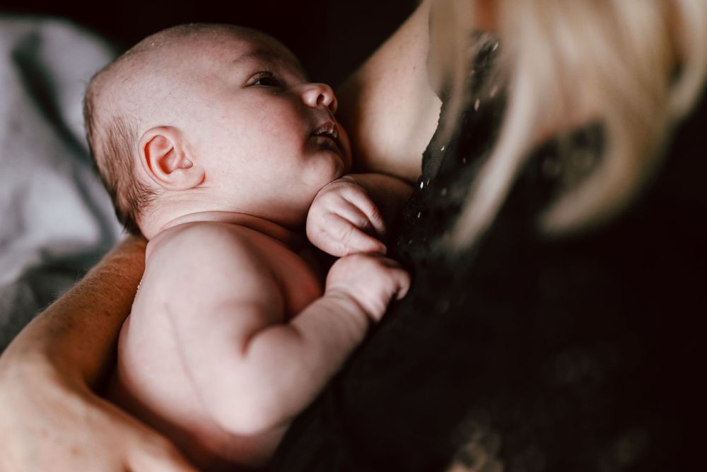 A baby lays peaceful and calm as blurred parental hands provide loving comfort and care.