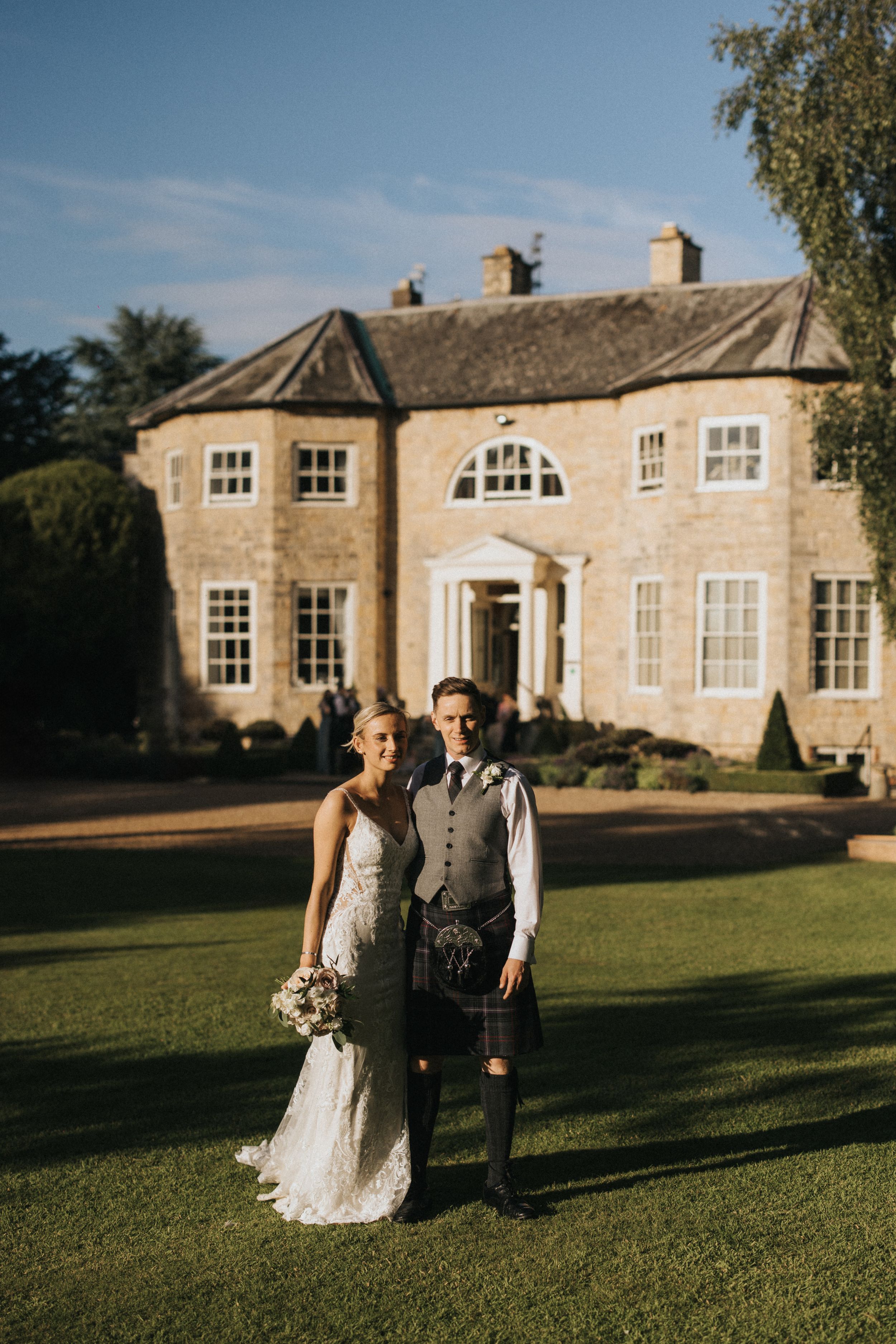 A couple stands on a manicured lawn in front of Washingborough Hall - taken by Grimsby photographer.