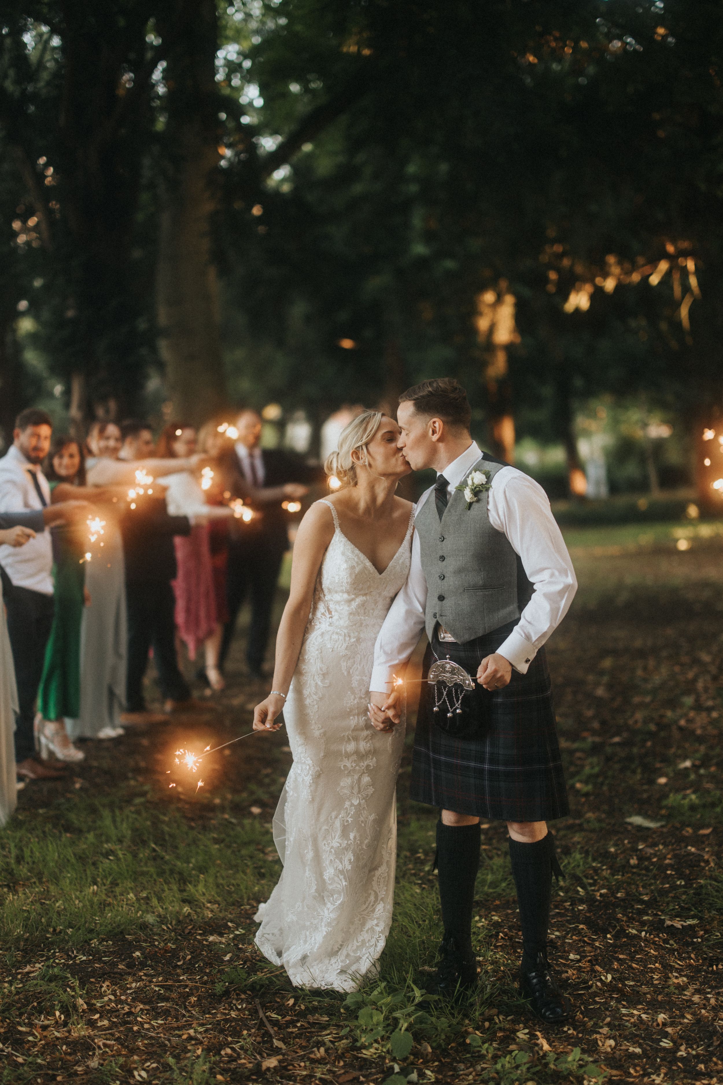 Romantic evening wedding photos showing couples with sparklers in a wooded garden setting at dusk at Washingborough Hall.