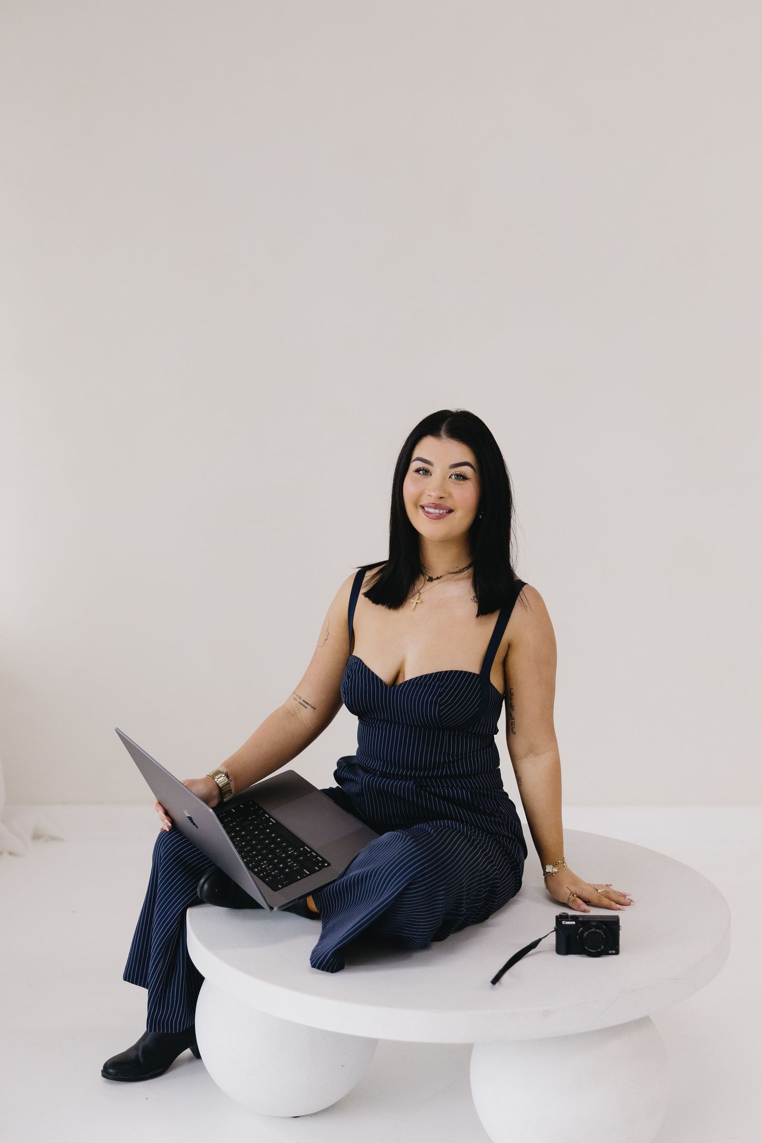 A person in a black outfit poses against a grey backdrop in a series of similar promotional style photos.