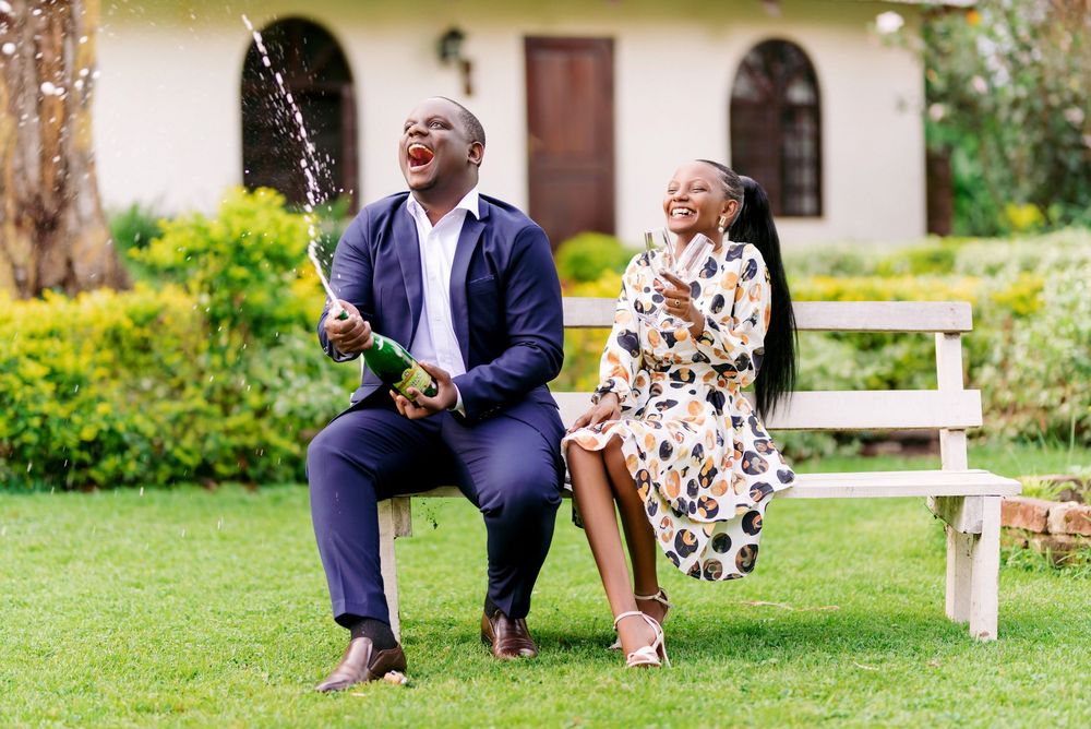 Couple enjoying a playful moment on a grassy lawn outside a building.
