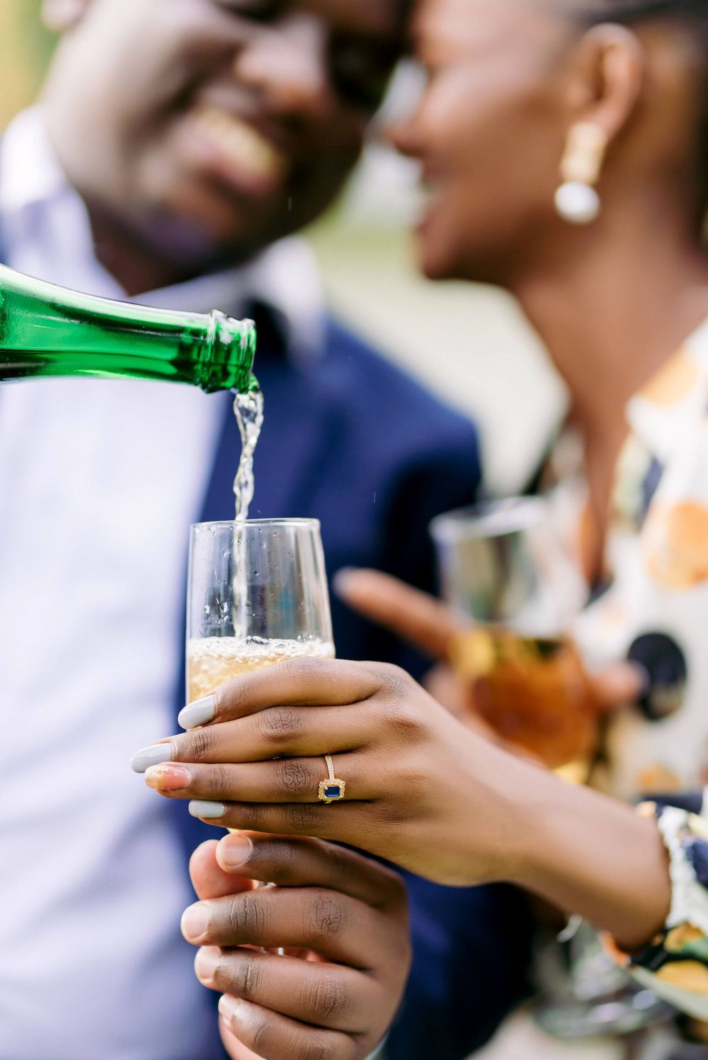 Close-up of hands holding drinks and toasting at an outdoor celebration.