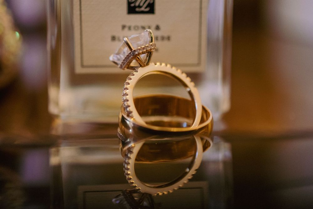 Close-up of gold and diamond wedding rings displayed on a reflective surface.