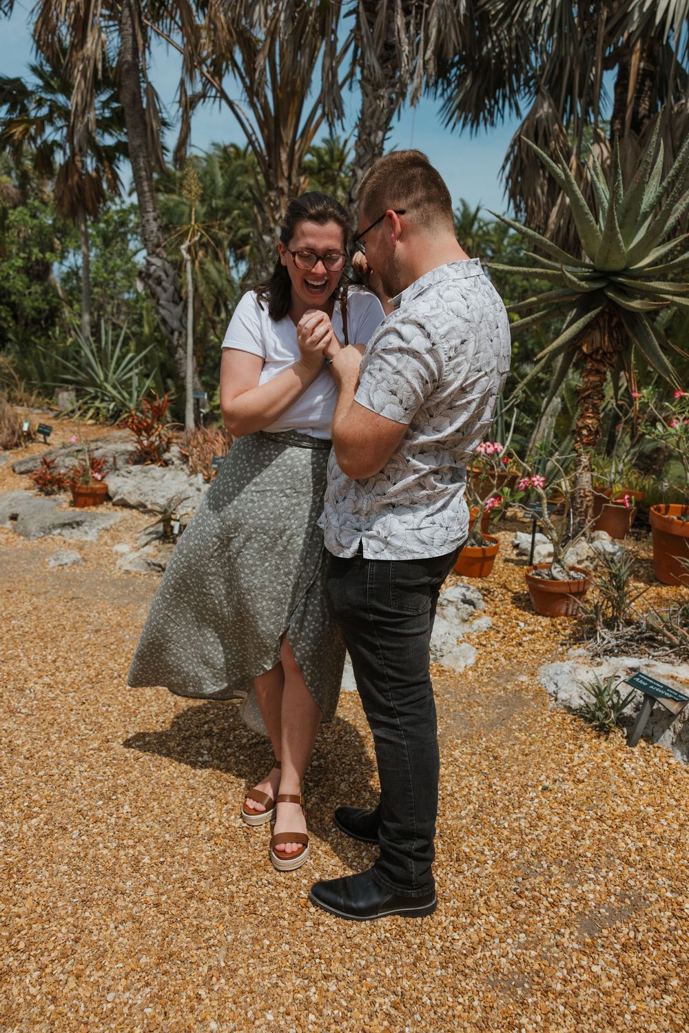 A romantic proposal moment captured in a desert garden setting with succulents and cacti in the background.