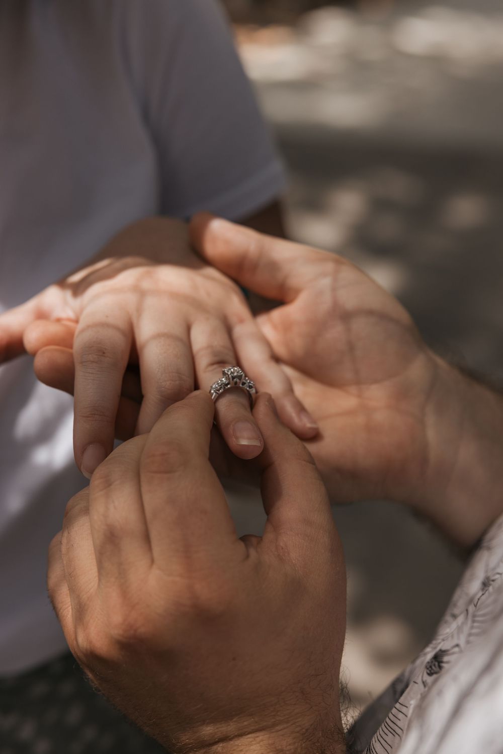 Close-up shot of hands placing an ornate engagement ring during a romantic proposal moment.