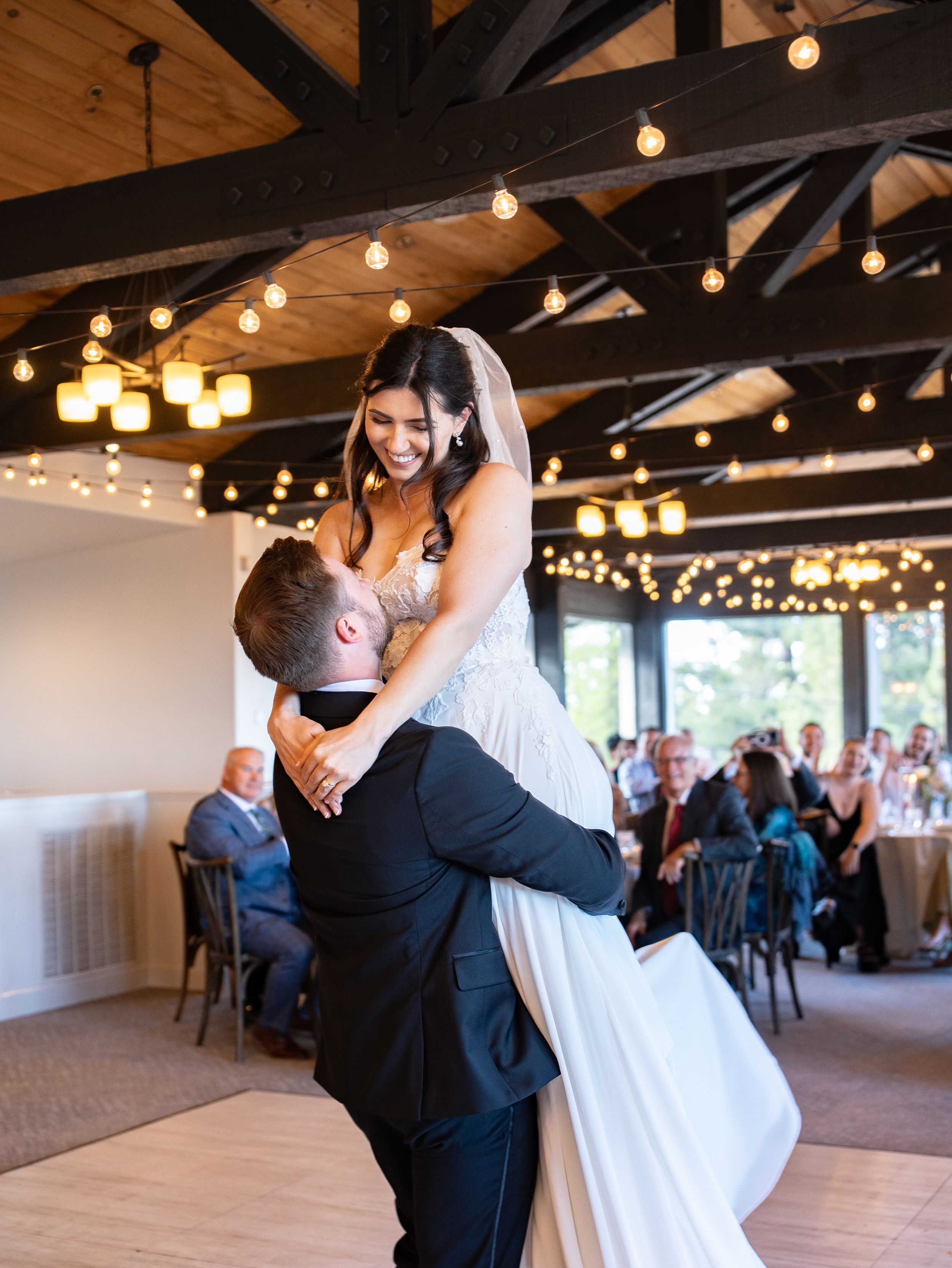 A couple shares a romantic first dance together at their wedding reception under warm bistro lights.