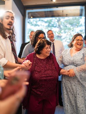A group of people share a joyful moment together at an indoor gathering, laughing and smiling warmly.