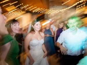 Motion blurred photo of people dancing at a wedding reception with colorful lighting effects.