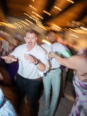 Blurred motion sequence of wedding reception guests dancing energetically on a dimly lit dance floor.