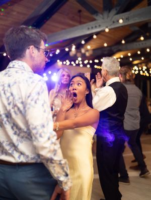 Dancers in formal attire enjoying a lively celebration with string lights and glowing ambiance at an indoor venue.