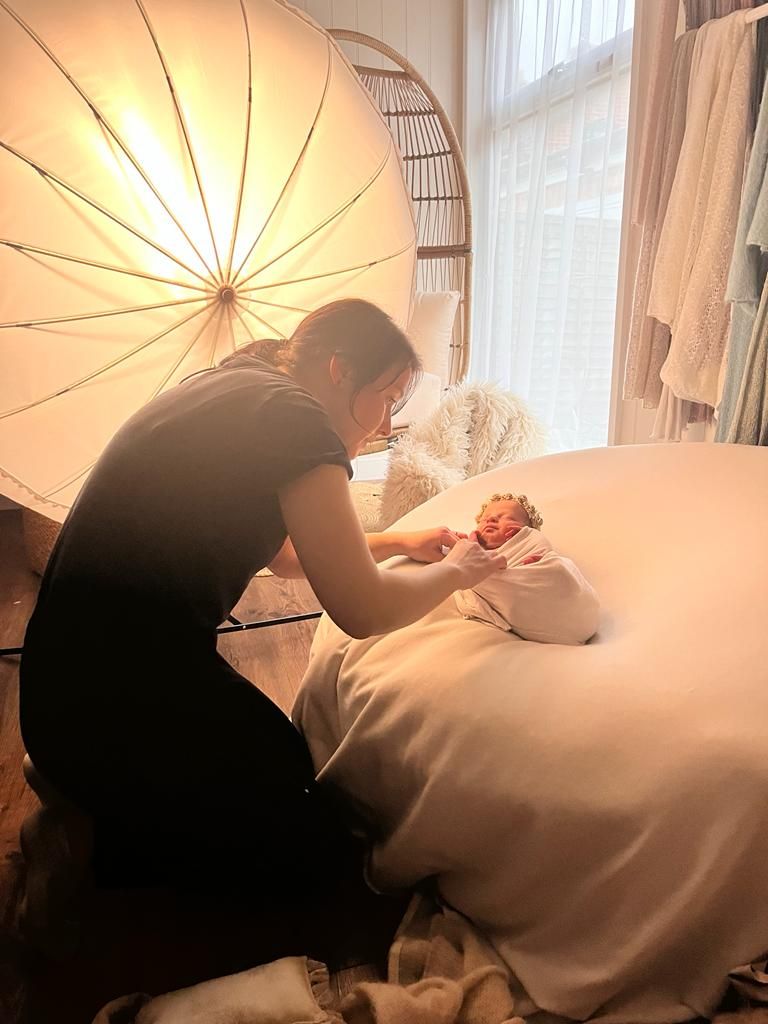 Londons best Professional photographer adjusts lighting equipment with large softbox umbrella while setting up for indoor photo shoot.