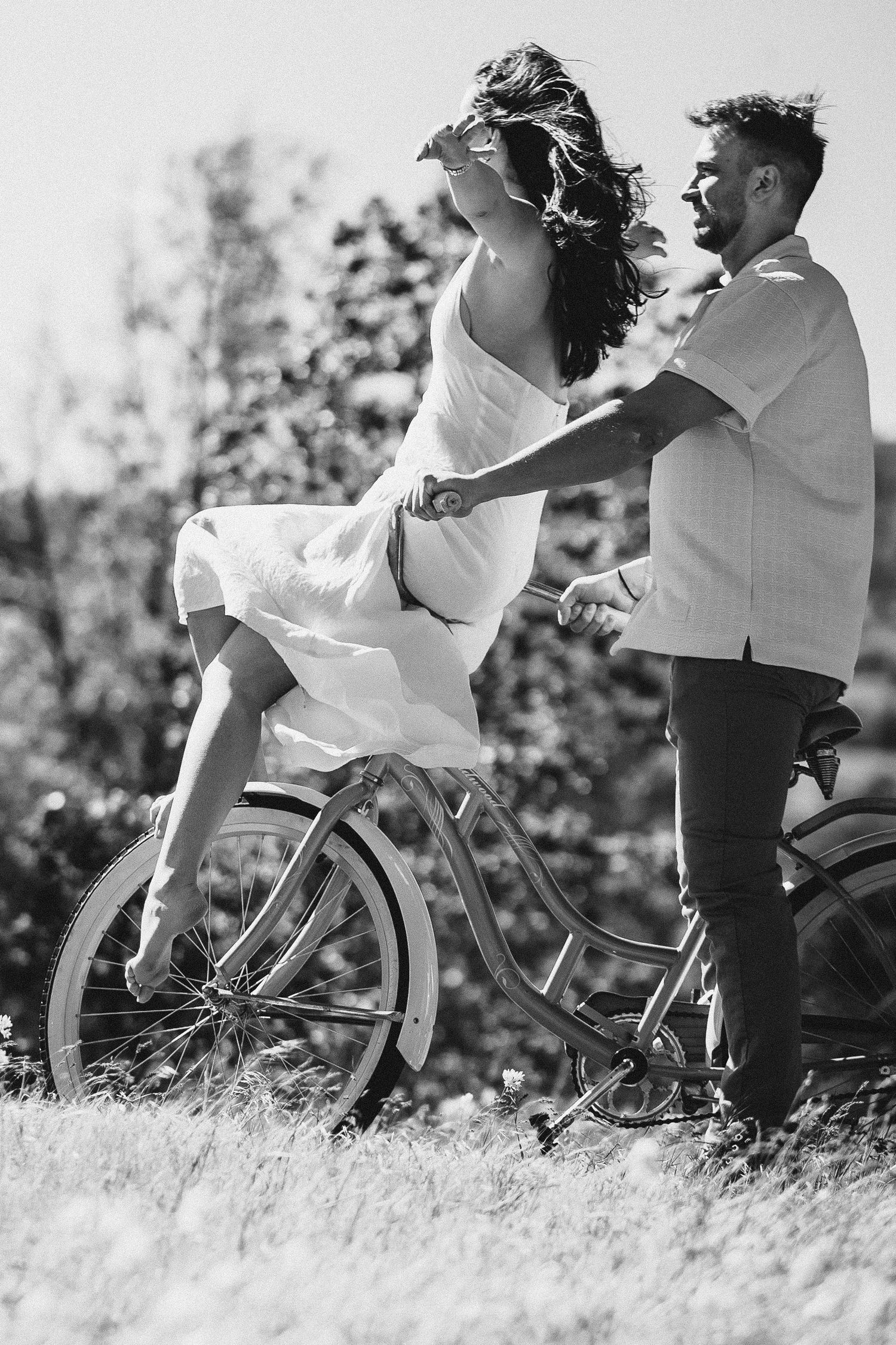 Natalie rides on her fiance's bicycle handlebars with arms outstretched and wind in her hair during her engagement session in Washington.