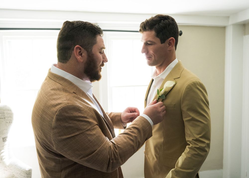 Men in suits showcase professional etiquette while checking each other's outfits during a formal gathering.