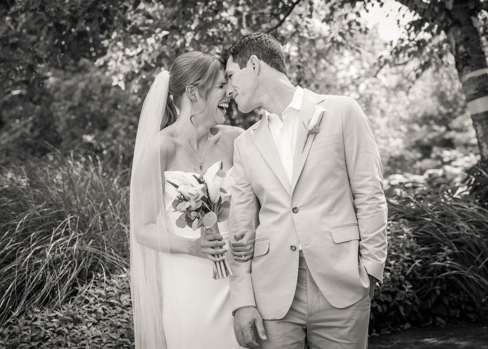A romantic black and white wedding photo showing a couple in a garden setting sharing an intimate moment.