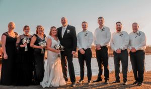 Wedding party members stand in a row against a desert landscape during golden hour sunset with warm lighting.
