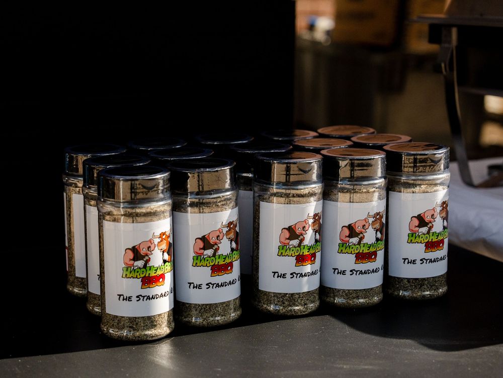 Row of five glass spice jars with matching labels displayed on a dark countertop.