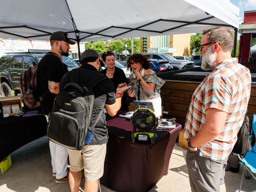 People gather around an outdoor tent for food service and social interaction at a casual event.