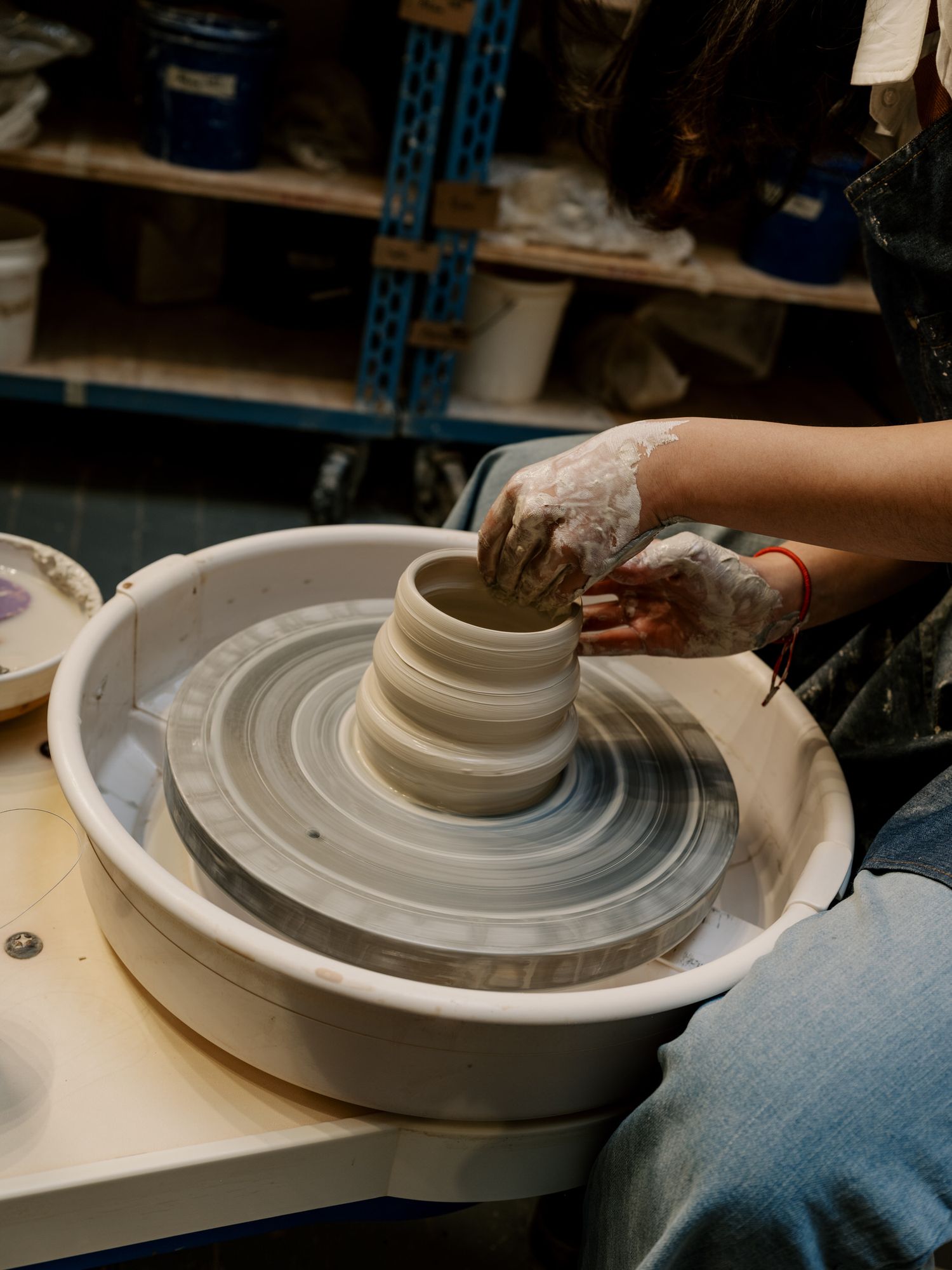 Close-up of hands shaping clay on a spinning pottery wheel during ceramic making process.