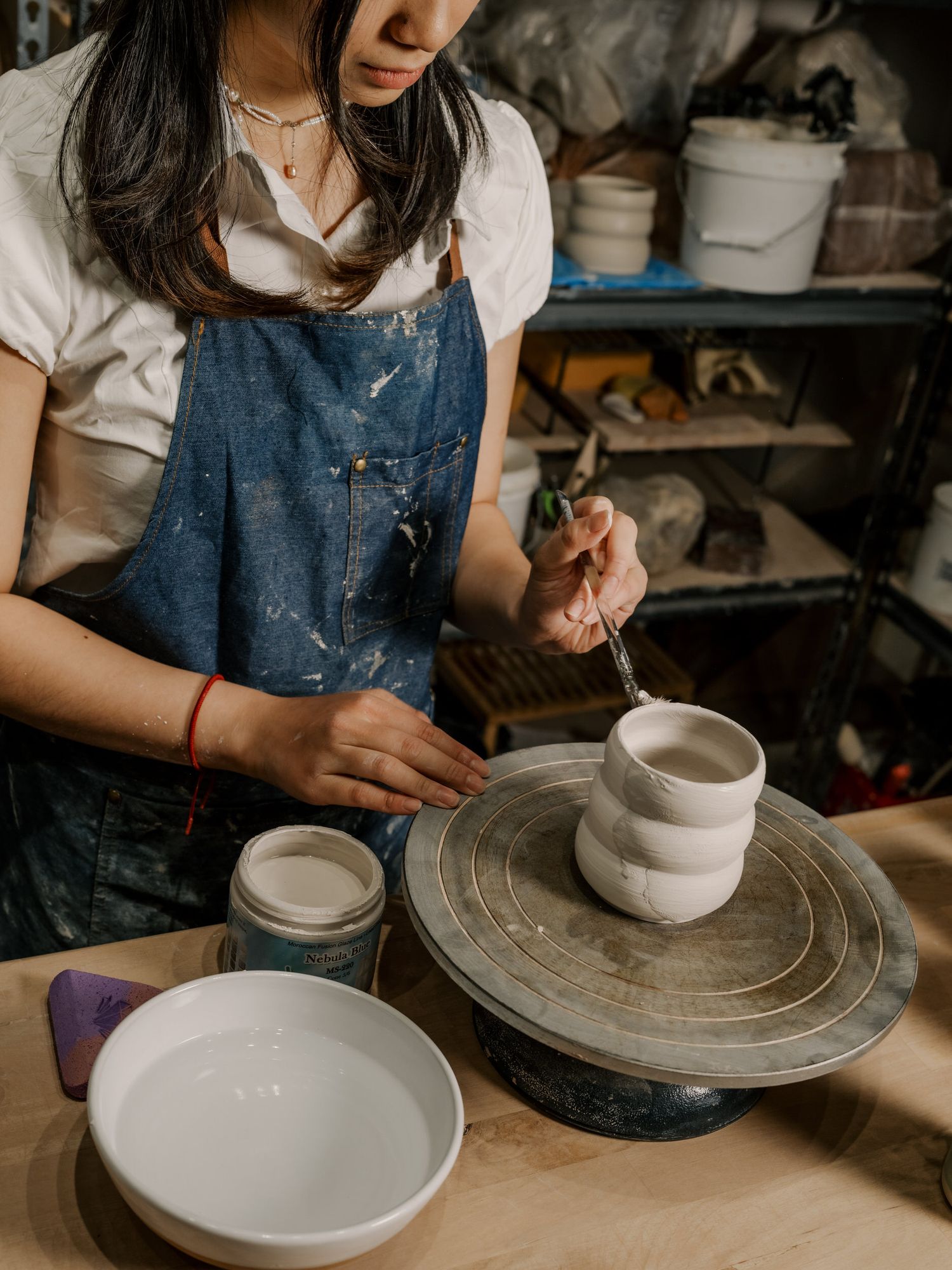 Close-up of pottery wheel with white ceramic bowls being crafted in studio.
