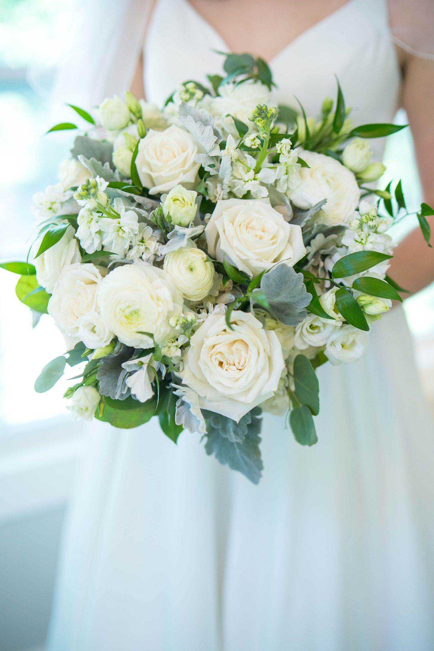 White rose and eucalyptus wedding bouquet held against a light blue background. Kelly Photography Atlanta Wedding Session Mableton GA