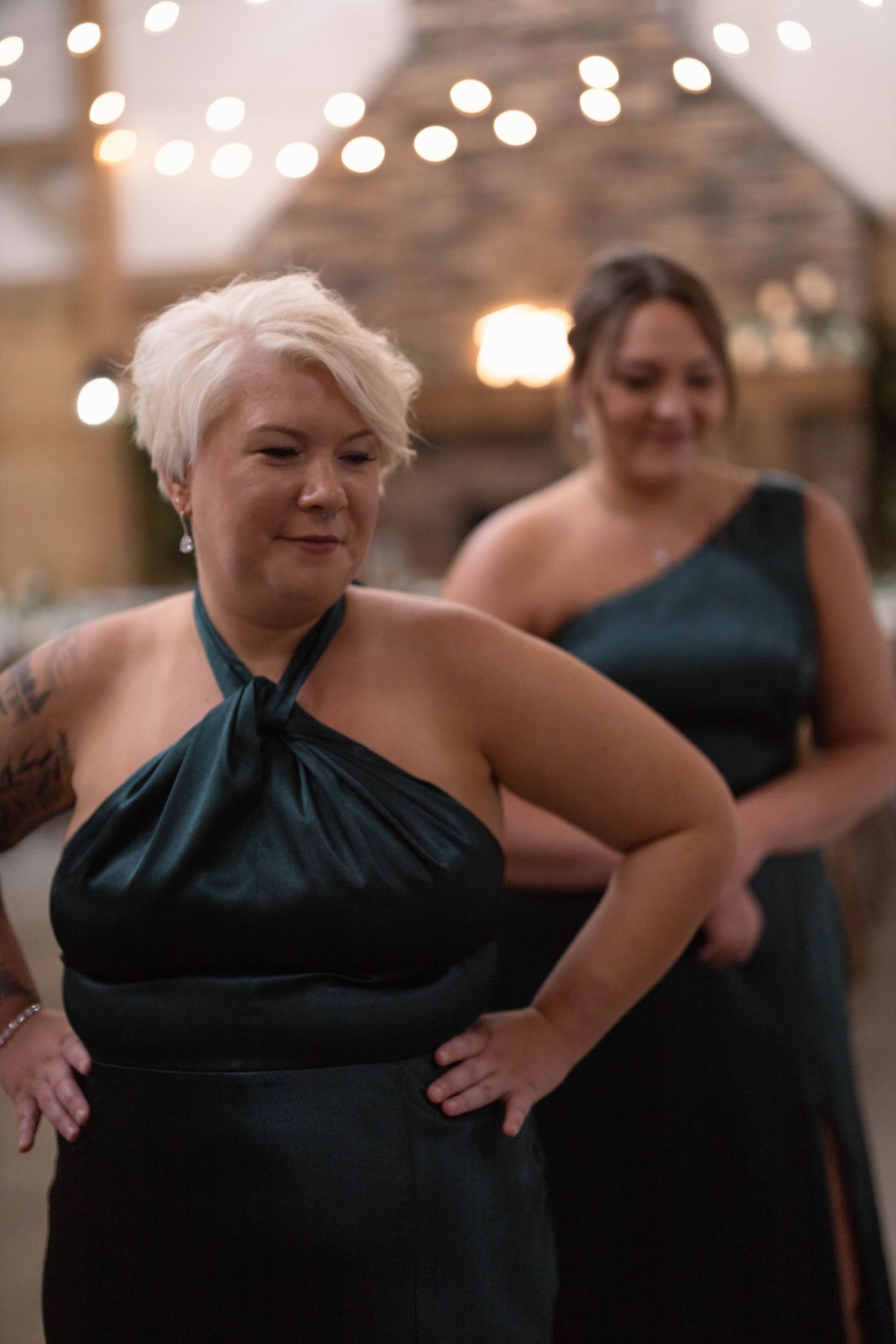 Woman in black one-shoulder dress smiling and posing in multiple sequential shots with bokeh lights in background.